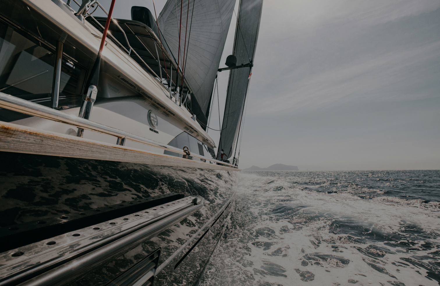 Eine weiße Yacht auf dem Meer. Die Kamera zeigt die Yacht von der Seite in Fahrtrichtung.